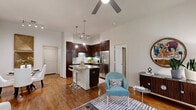 Located at 1900 Yorktown Street in Houston's Galleria area, this single-story residence offers three bedrooms and three bathrooms within a thoughtfully designed floor plan. The open-concept living room greets with warm hardwood flooring, a ceiling fan, and a row of large windows that frame lush greenery, filling the space with abundant natural light. The kitchen is a functional highlight, featuring rich dark wood cabinetry extending to impressive heights, granite countertops, a breakfast bar island with bar seating, subway tile backsplash, and a full suite of stainless steel appliances — including a gas range and French door refrigerator. The bedrooms are carpeted and well-proportioned, with ceiling fans, natural light from large windows, and generous closet space including a walk-in closet with multi-tier wire shelving. The primary bedroom connects to an en-suite bathroom equipped with a deep soaking tub set into neutral tile surround. A second bathroom features a tub-shower combination with tile surround and granite vanity. Three hallways provide smooth connectivity throughout the unit, while two closets offer additional storage. The overall ambiance is clean, contemporary, and bright — a comfortable and well-appointed Houston residence.