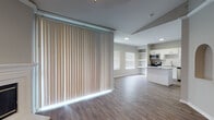 This single-floor residence offers a thoughtfully designed open-concept layout that seamlessly connects the living area to the kitchen. The main living space is bright and airy, featuring durable hardwood-style flooring throughout and large vertical blinds that filter natural light. A pendant light fixture adds a warm focal point to the open living area, which also includes a charming arched wall niche as an architectural detail.

The kitchen is well-equipped with white shaker-style cabinetry, granite countertops, a decorative hexagonal tile backsplash, and a full suite of stainless steel appliances including a refrigerator, range, microwave, and dishwasher. A kitchen island provides additional prep and counter space.

The bedrooms are generously sized with large windows that allow ample natural light, ceiling fans, and a mix of hardwood-style flooring and area rugs. The bathrooms are finished with clean, modern fixtures — one features a vanity with granite countertops, white cabinetry, and a large mirror, while another includes a combination tub and shower with sliding glass doors and white tile surround. Neutral gray walls throughout the space create a calm, cohesive aesthetic ideal for a variety of interior styles.