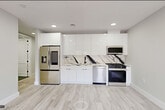 Located at 187 Culver Avenue in Jersey City, NJ, this thoughtfully designed 2-bedroom, 1-bathroom unit offers a modern and cohesive living experience across a single floor. Light-toned hardwood flooring flows seamlessly throughout, complementing the crisp white walls and clean architectural lines that define the space.

The open kitchen and living area serves as the heart of the unit, featuring a striking kitchen outfitted with high-gloss white cabinetry, a dramatic black-and-white marble-style backsplash, stainless steel appliances including a gas range, dishwasher, over-the-range microwave, and a French door refrigerator. Recessed lighting illuminates the space efficiently, enhancing the sleek, contemporary design.

The two bedrooms are bright and well-proportioned, each featuring large black-framed windows that invite natural light and neighborhood views. The primary bedroom includes access to a built-in closet with dedicated shelving, maximizing storage and organization. A second bedroom with its own window provides flexibility for guests or a home office.

The bathroom is finished with floor-to-ceiling marble-style wall tiles, grey slate-toned floor tiles, and matte black fixtures and hardware, creating an elevated and refined aesthetic. A clean hallway connects the private areas of the unit, maintaining a functional and organized layout throughout.