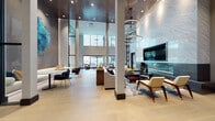 This elegantly designed single-floor amenity space makes a striking impression through its architectural scale and refined modern aesthetic. The main lounge area commands attention with dramatic double-height ceilings clad in dark wood paneling, from which sculptural circular pendant lights descend at varying levels, creating a layered, luminous atmosphere. Light-toned wide-plank hardwood flooring extends throughout, grounding the space with warmth.

The lounge is thoughtfully arranged into distinct social zones. A living area centered on a textured herringbone-patterned feature wall houses a wall-mounted television above a sleek linear fireplace, surrounded by mid-century modern seating in white and walnut. Adjacent dining and casual seating vignettes are furnished with navy velvet accent chairs, adding rich color contrast. Curated artwork and sculptural wall installations, including blue glass and abstract pieces, punctuate the space at key intervals.

A full catering kitchen features herringbone-tiled flooring, dark cabinetry, white quartz countertops, a dishwasher, wine refrigerator, and wall-mounted television, making it well-suited for entertaining. Expansive floor-to-ceiling windows and sliding glass doors throughout flood the interior with natural light while providing direct visual and physical access to an outdoor pool terrace. A decorative black metal geometric screen partition adds architectural interest near the transition zones.