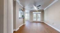 This well-appointed two-story home offers 1,570 square feet of living space across three bedrooms and three bathrooms. The main floor spans 940 square feet and features an open living room with warm hardwood-style flooring, crown molding, a ceiling fan, and a decorative column framing the staircase. The galley-style kitchen is outfitted with rich dark wood cabinetry, dark granite countertops, a stone tile backsplash, and a full suite of stainless steel appliances including a refrigerator, range, microwave, and dishwasher. The upper floor covers 620 square feet and hosts the bedrooms, including a 220-square-foot primary bedroom with French doors opening to a private balcony and a ceiling fan. Additional bedrooms feature plush carpet, crown molding, ceiling fans, and ample natural light — one notably includes a bay window. The bathrooms are finished with dark granite vanity tops and rich wood cabinetry; the primary bath includes a soaking tub and a dual-sink vanity. A dedicated closet with built-in shelving and a separate laundry room housing a full-size washer and dryer complete this functional and thoughtfully designed home.