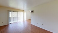 Located at 9675 Genesee in San Diego, this single-story unit offers a straightforward, functional layout with consistent finishes throughout. The living area is a bright, open space finished with warm wood-style flooring that extends through the main areas. A large sliding glass door fitted with vertical blinds fills the room with natural light and provides outdoor views, while a wall-mounted air conditioning unit ensures year-round comfort. A textured ceiling adds subtle visual interest overhead.

The galley-style kitchen runs parallel along one wall, featuring white cabinetry above and below, dark countertops with a double-basin sink, and white appliances including a coil-top range and refrigerator. A flush-mounted ceiling light provides functional illumination in this efficient cooking space.

The bedroom is carpeted and receives generous natural light through a large window dressed with vertical blinds, creating a calm and comfortable atmosphere. Neutral wall tones throughout the unit contribute to a clean, cohesive look.

The bathroom includes a single-sink vanity with a mirrored medicine cabinet, a toilet, and a full tub-shower combination with chrome fixtures. The overall design is practical and well-maintained, suited for straightforward, comfortable living in San Diego.