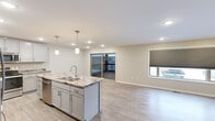 This single-floor residence offers a thoughtfully designed layout across a comfortable footprint, featuring 2 bedrooms, 3 bathrooms, and an open-concept kitchen and living area. The kitchen serves as a central highlight, showcasing gray shaker-style cabinetry, striking marble-patterned granite countertops, stainless steel appliances—including a refrigerator, range, and built-in microwave—and a functional island with pendant lighting overhead. Light wood-look flooring runs throughout the main living areas, contributing to a clean, contemporary aesthetic. The living room flows naturally from the kitchen and opens to an outdoor balcony via sliding glass doors, allowing for natural light and outdoor access.

The two bedrooms are finished with neutral wall tones and plush carpet. The generously sized primary bedroom provides ample space and is complemented by a well-organized walk-in closet featuring double hanging rods and shelving. The three bathrooms include a full bathroom with a wide vanity, gray cabinetry, integrated storage tower, and modern lighting, as well as a secondary bathroom with a walk-in shower. A hallway connects the private areas of the home, enhancing the overall flow of the layout.