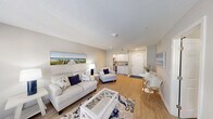 Located at 300 W Airport Blvd in Sanford, Florida, this thoughtfully designed one-bedroom, two-bathroom unit offers a functional and cohesive layout across a single floor. The living room serves as the heart of the space, featuring light wood-style flooring, neutral gray walls, and a textured ceiling. Large double doors flood the room with natural light and lend an open, airy feel. A coastal aesthetic is carried throughout, complemented by crisp white trim and clean lines.

The compact kitchen is efficiently appointed with white shaker-style cabinetry, granite-look countertops, a stainless steel refrigerator, range, and microwave — offering full cooking functionality within a modest footprint. Adjacent to the living area, a dining nook provides an intimate space for everyday meals.

The bedroom is a calm retreat with a textured ceiling, wood-style flooring, and a window that allows natural light. It connects directly to a dedicated closet with built-in shelving and hanging rods for organized storage. The two bathrooms include a clean, all-white walk-in shower with grab bars and a toilet, designed with both accessibility and simplicity in mind. Throughout the unit, a consistent coastal-neutral color scheme and warm flooring create a cohesive, welcoming ambiance.