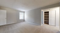 Located at 6660 Mableton Pkwy SE in Mableton, Georgia, this single-floor unit offers a straightforward and functional layout designed for comfortable living. The interior is finished with neutral gray walls and white trim throughout, creating a clean, cohesive aesthetic. Plush carpeting covers the living and bedroom areas, lending warmth underfoot, while the kitchen and entryway feature wood-look vinyl plank flooring for easy maintenance. The kitchen is equipped with warm-toned wood cabinetry, light countertops, and white appliances including a refrigerator, electric range, and dishwasher. A window above the sink area allows natural light to fill the space, and a secondary door provides direct exterior access. The living area is generously sized with open wall space and direct access to other areas of the unit. The bedrooms are well-proportioned, each featuring carpeted floors, natural light from windows, and ample closet storage — one bedroom notably includes built-in shelving. A full bathroom with a soaking tub and a window rounds out the unit. With a textured ceiling throughout and a neutral palette, this space offers a solid foundation for personalization.