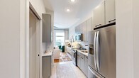 This well-appointed 1-bedroom, 1-bathroom residence makes excellent use of its single-floor layout, delivering a modern and cohesive living experience. The open-concept design connects the kitchen and living area seamlessly, creating an efficient and inviting flow throughout the space.

The kitchen is outfitted with sleek grey flat-front cabinetry extending to the ceiling for ample storage, stainless steel appliances including a French-door refrigerator and range, a white herringbone tile backsplash, and a clean white countertop with a matte black faucet — all contributing to a sharp, contemporary aesthetic.

The living area benefits from large windows that invite abundant natural light and offer views of the surrounding neighborhood. Light wood-tone flooring runs throughout, enhancing the bright and airy feel of the space.

The bedroom is generously proportioned, featuring floor-to-ceiling windows with outdoor views, a ceiling fan, and neutral grey walls that create a calm, restful atmosphere.

The bathroom is distinctively finished with bold monochrome penny-tile detailing in the shower/tub surround, paired with grey cabinetry, a framed mirror, and matte black hardware, offering a modern and stylish contrast to the rest of the home's palette.