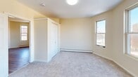 Located at 18-24 York St in Hartford, CT, this four-bedroom, one-bathroom unit offers a practical and functional layout across a single floor. The space is finished with warm cream-toned walls throughout, creating a consistent and neutral aesthetic. The kitchen features warm wood cabinetry with upper and lower storage, a granite-style countertop with a stainless steel sink, and light wood-style vinyl flooring that extends into the adjacent living area. Natural light enters through a window framing views of the surrounding brick urban streetscape. Each of the four bedrooms is carpeted and includes baseboard heating, with most rooms featuring closet storage. The generously sized primary bedroom stands out with a striking angled bay configuration of three windows, offering abundant natural light and open views of the Hartford cityscape. Additional bedrooms vary in size and include built-in closets with wood-paneled or sliding doors. The bathroom is efficiently designed with a full-size soaking tub with shower, a white vanity with sink, toilet, and light wood-style vinyl flooring. A staircase provides access to the unit. The overall layout is well-organized, making efficient use of the available space for comfortable multi-bedroom living.