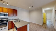 Located at 805 Mauldin Road in Greenville, SC, this single-floor residence offers two bedrooms and two bathrooms within a well-appointed, efficiently designed layout. The open-concept kitchen is a standout feature, showcasing rich cherry wood cabinetry, granite countertops, and a full suite of stainless steel appliances including a refrigerator, range, and microwave. A peninsula with a built-in sink and breakfast bar seating connects the kitchen seamlessly to the living area, which features light hardwood-style flooring, crown molding, and French doors that invite natural light and outdoor views. Both bedrooms are carpeted and finished with neutral tones, offering a comfortable, quiet retreat. The spacious primary bedroom is notably generous in size and includes access to a walk-in closet equipped with wire shelving and hanging rods. The two bathrooms are clean and functional; one features tile-surround tub/shower combo and hardwood-style flooring, while the second offers a white tub/shower unit with a curved curtain rod. A hallway connects the main living spaces, adding to the flow of the floor plan. Crown molding and recessed lighting are consistent throughout, lending a polished, cohesive aesthetic to the entire residence.