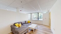 Located at 7040 Oxford Ave in Philadelphia, PA, this efficiently designed single-floor unit offers a well-organized layout encompassing a living room, kitchen, bedroom, bathroom, and closet. Light wood laminate flooring runs throughout the main living areas, lending a clean and cohesive aesthetic. The living room is bright and open, featuring large windows with vertical blinds that invite natural light and offer views of surrounding greenery. A drop tile ceiling with recessed lighting maintains a modern, uniform look across the space. The kitchen is positioned adjacent to the living area and is outfitted with white cabinetry, a stainless steel range with oven, a microwave, and a sink — providing all essential amenities in a compact, functional arrangement. The bedroom is a calm, well-proportioned room with its own window and a wall-unit HVAC system, along with a closet for storage. The bathroom features grey subway-style wall tiles, warm yellow floor tiles, a white vanity with mirror, and an accessible walk-in shower equipped with grab bars and a handheld showerhead. Overall, the unit presents a clean, modern, and practical living environment suited for comfortable everyday living.