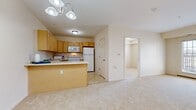 Located at 4400 E Lake Rd in Erie, PA, this 2-bedroom, 1-bathroom residence offers a practical and well-organized single-floor layout. The open-concept kitchen and living area serve as the heart of the home, where warm honey-toned cabinetry, a peninsula breakfast bar, and white appliances — including a refrigerator, electric range, and over-the-range microwave — create a functional cooking space. The kitchen transitions seamlessly into the living room, which is carpeted in a neutral beige tone and features French doors that invite natural light and provide access to an outdoor area. A ceiling-mounted light fixture with brushed nickel accents adds a decorative touch to the shared space. Both bedrooms are carpeted and finished with clean white walls, offering a bright and neutral canvas. The primary bedroom is a comfortable size and includes a built-in closet with wire shelving for organized storage. The second bedroom also features closet access and a window with outdoor views. The bathroom is appointed with tile flooring, a well-lit vanity mirror, and warm wood-toned cabinetry, consistent with the design palette found throughout the residence. Clean lines, neutral finishes, and a cohesive color scheme give this home a move-in-ready feel.