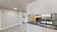 This single-floor, 2-bedroom, 2-bathroom unit in Green Bay, Wisconsin offers a clean, modern aesthetic throughout. Light-toned luxury vinyl plank flooring flows consistently across all rooms, complementing the neutral beige and white color palette that gives the space a bright, cohesive feel.

The living area is generously sized and filled with natural light from a sliding glass door that opens onto a private balcony, offering outdoor views of the surrounding neighborhood. A pass-through window connects the living space to the kitchen, creating an open, communicative layout. The kitchen is efficiently designed with white shaker-style cabinetry, dark granite-style countertops, black hardware accents, and stainless steel appliances including a refrigerator, range, and dishwasher.

Both bedrooms are well-proportioned, each featuring a dedicated window that brings in natural light and baseboard heating. The two bathrooms are finished with light, clean materials—one includes a white vanity with ample storage and a tub-shower combination, while the second bathroom mirrors a similar functional design with updated black fixture accents. The overall ambiance is contemporary, understated, and move-in ready.