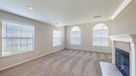 Located at 27701 Detroit Road in Westlake, Ohio, this single-floor, 2-bedroom, 2-bathroom residence offers a thoughtfully designed layout with comfortable living spaces throughout. The combined kitchen and living room area serves as the heart of the home, anchored by a classic white-mantled fireplace with a tile hearth that adds warmth and character to the living space. The kitchen is well-equipped with white shaker-style cabinetry, stainless steel appliances including a range, microwave, and dishwasher, complemented by stone-look countertops, a built-in wine rack, and light hardwood-style flooring. The primary bedroom is generously proportioned and features a striking pair of arched windows that flood the room with natural light, along with plush carpet and a dedicated walk-in closet outfitted with wire shelving for ample storage. The en-suite bathroom includes a white vanity with stone-look countertops and dual mirrors. The second bedroom is comfortably sized, carpeted, and includes a standard closet. A carpeted hallway with built-in shelving connects the living areas to the bedrooms. Neutral tones and textured ceilings throughout create a clean, cohesive aesthetic.