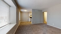Located at 6221 East 36th Street in Tulsa, Oklahoma, this single-floor unit offers a practical and comfortable layout with thoughtfully updated finishes throughout. The open living area features warm, neutral-toned carpet and is seamlessly connected to an adjacent dining or flex space finished with wood-look flooring, creating a natural transition between areas. A partial dividing wall separates the living space from the kitchen, maintaining an open feel while defining each zone. The kitchen is well-appointed with crisp white cabinetry, granite-style countertops, a double-basin sink, and black appliances including a range, refrigerator, and dishwasher — all set atop durable wood-look flooring. The bedroom is generously sized, filled with natural light from a large window with blinds, and features plush carpet and a ceiling fan with light fixture. A second carpeted room with its own window and closet provides additional flexible living space. The bathroom is a standout, showcasing marble-patterned tile surround around the soaking tub and shower, a granite-top vanity with white cabinetry, and wood-look flooring. Clean gray and neutral wall tones carry throughout the unit, lending a cohesive, modern aesthetic to this well-maintained Tulsa residence.