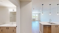 Located at 2463 Hogum Bay Rd NE in Lacey, WA, this thoughtfully designed one-bedroom, one-bathroom unit offers a clean, modern aesthetic throughout. Light wood-style flooring runs continuously across the entire space, creating a cohesive and airy feel.

The open-concept kitchen and living area serves as the heart of the unit. The kitchen is equipped with stainless steel appliances, including a gas range and refrigerator, complemented by taupe cabinetry with matte black hardware. A large island with a white quartz countertop and integrated sink anchors the space, with stylish pendant lighting hanging above. Ample lower cabinetry provides generous storage.

The living area features a glass-paneled door leading to an exterior space, allowing natural light to filter in. The bedroom is a well-proportioned room with large windows that frame views of the surrounding greenery and neighborhood, filling the space with abundant natural light. A double sliding-door closet offers practical storage.

The bathroom maintains the unit's clean design language with light flooring, a vanity with cabinetry, and a bathtub with shower. Throughout the unit, neutral white walls and consistent finishes create a bright, move-in ready environment well-suited for comfortable everyday living.