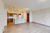 Located at 173 Pump Dr in Burlington, WA, this one-bedroom apartment offers a practical and well-designed layout across a single floor. Light wood-style luxury vinyl plank flooring extends throughout the unit, lending a clean and cohesive aesthetic to every room.

The open-concept kitchen and living area forms the heart of the space. The kitchen features warm wood cabinetry, white appliances including a range, microwave, dishwasher, and refrigerator, as well as a peninsula with a sink and light-toned countertops. Pendant lighting over the peninsula adds a finishing touch. The living area adjacent to the kitchen is bright and open, benefiting from large windows and a glass door that invite natural light and provide views of the surrounding exterior.

The bedroom is a comfortable size, with a window allowing additional natural light, a ceiling-mounted light fixture, and a floor vent for climate control. It connects to a generously sized walk-in closet outfitted with wire shelving along multiple walls, offering ample storage. The bathroom includes a wood-toned vanity with an integrated sink, a large mirror, and a clean, well-lit layout.

Additional features include a set of double louvered utility doors near the kitchen, providing convenient in-unit storage or laundry access. The overall ambiance is clean, neutral, and move-in ready.