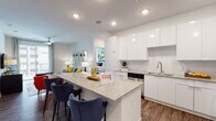 Located at 1270 Spring St NW in Atlanta's vibrant Midtown neighborhood, this single-floor residence offers a thoughtfully designed open-concept layout with contemporary finishes throughout. The kitchen serves as a central highlight, featuring sleek white cabinetry extending to the ceiling, granite countertops, a large island with seating, a subway tile backsplash, and stainless steel appliances including a range, microwave, and refrigerator. The kitchen flows seamlessly into the living area, which is bathed in natural light from large sliding glass doors opening to a private balcony with urban views. Wood-style flooring runs consistently throughout the space, adding warmth and cohesion to the modern aesthetic. The bedroom is generously proportioned, offering ample space and access to a walk-in closet outfitted with wire shelving systems. The en-suite bathroom features granite countertops, a white undermount sink, a large vanity mirror with modern lighting, and a glass-enclosed shower. Recessed lighting and ceiling fans are found throughout, ensuring both style and comfort. The overall ambiance is clean, bright, and contemporary, making this a well-appointed urban residence in the heart of Atlanta.