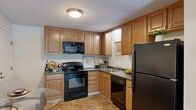 Located at 130 W Clarke St in Manchester, NH, this two-bedroom, one-bathroom residence offers a practical and well-organized single-floor layout designed for comfortable everyday living. The combined kitchen and living area forms the heart of the home. The kitchen features warm-toned wood cabinetry, dark countertops, black appliances including a range, microwave, dishwasher, and refrigerator, and durable tile flooring. Adjacent to the kitchen, a dedicated dining nook provides space for a small table, ideal for daily meals. The living room is carpeted and bright, with a sliding glass door that opens to a private balcony, allowing natural light to fill the space and offering outdoor views. Both bedrooms are carpeted and finished with neutral walls, creating a calm and restful atmosphere. The spacious primary bedroom includes a window with outdoor views and ample room for a full furniture arrangement. The second bedroom also features a window and versatile floor space suitable for a variety of uses. The full bathroom is finished with tile flooring and includes a tub-shower combination. Throughout the residence, baseboard heating ensures year-round comfort, and the consistent neutral color palette gives the entire space a clean, cohesive feel.