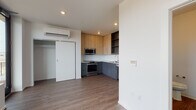 Located at 15 N Grant Street in Spokane, Washington, this single-floor unit offers a thoughtfully designed layout with contemporary finishes throughout. The open living area is defined by large, black-framed floor-to-ceiling windows and a glass door that flood the space with natural light while providing views of the surrounding neighborhood. Hardwood-style flooring runs continuously throughout, lending a cohesive, modern feel.

The kitchen is well-appointed, featuring stainless steel appliances including a refrigerator, range, microwave, and dishwasher. Cabinetry combines warm wood-tone upper cabinets with sleek grey lower units, complemented by clean white countertops and a single-basin sink. Recessed lighting adds to the bright, functional atmosphere. A wall-mounted mini-split climate control unit ensures year-round comfort.

A sliding door closet provides dedicated storage within the living space. The bathroom is efficiently designed with wood-style flooring, a vanity, toilet, and grab bar for added accessibility. The overall aesthetic is clean and minimalist, with white walls and modern fixtures creating a fresh, move-in-ready environment suited for urban living in Spokane.