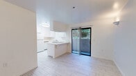 Located at 454 Requeza St in the coastal city of Encinitas, California, this one-bedroom, one-bathroom unit offers a thoughtfully organized layout across a single floor. The interior is finished in a clean, all-white palette that enhances the sense of brightness and openness throughout the space.

The main living and kitchen area is the heart of the unit, where light wood-style flooring runs seamlessly underfoot. The kitchen features white cabinetry extending to the ceiling for ample storage, tile countertops, a peninsula with bar-height seating potential, and a full suite of appliances including a refrigerator. A large sliding glass door floods the area with natural light and provides direct access to a private outdoor patio with lush greenery views.

The bedroom is a well-proportioned, serene retreat with the same wood-style flooring, a window dressed with vertical blinds, and a sliding closet offering organized storage space. The room is simply designed with clean white walls, making it highly adaptable to various furnishing styles.

The bathroom is finished in a consistent white scheme, featuring a full soaking tub with shower, chrome fixtures, and a grab bar for added convenience. The entrance ties the layout together, providing a natural flow between all areas of the unit. Overall, the space presents a clean, modern, and practical living environment.