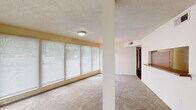 This single-floor, 2-bedroom, 1-bathroom unit in Memphis, Tennessee offers a functional and well-organized layout. The living area is bright and open, featuring wall-to-wall carpeting, a textured ceiling, and a wide bank of windows fitted with horizontal blinds that allow ample natural light to fill the space. A structural column adds architectural definition between the living and dining areas, while a chandelier overhead accents the dining space.

The kitchen is accessible via a pass-through window with a countertop bar, offering a connected feel to the main living area. Inside, the kitchen features warm wood cabinetry, granite-style countertops, hardwood flooring, and a dishwasher, providing practical functionality in a compact footprint.

Both bedrooms are carpeted and include ceiling fans with light fixtures and windows that bring in natural light. The primary bedroom is a comfortable size and connects to a walk-in closet equipped with shelving and a built-in surface for added storage versatility. The second bedroom also offers closet access.

The bathroom includes a full tub-shower combination, a single-sink vanity with wood cabinetry, and tile flooring. Hallways connect the rooms efficiently, completing the home's straightforward and practical floor plan.