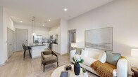 Located at 6163 Kempsville Cir in Norfolk, VA, this well-appointed 2-bedroom, 2-bathroom residence offers a thoughtfully designed single-level open-concept floor plan. The kitchen serves as a centerpiece of the home, showcasing white shaker cabinetry, dark granite countertops, a white subway tile backsplash, and a full suite of stainless steel appliances including a French door refrigerator, range, microwave, and dishwasher. A large kitchen island with dark countertop and seating for multiple guests is illuminated by elegant pendant lighting, making it ideal for both cooking and casual dining. The living room is bright and inviting, featuring large windows and a glass door that allow abundant natural light and views of the surrounding greenery. Light wood-style flooring flows throughout the main living areas, complementing the neutral color palette. The spacious primary bedroom includes plush carpeting, large windows, and a dedicated closet. The primary bathroom features white cabinetry, dark granite countertops, a wide vanity mirror, and direct access to a walk-in closet. The second bedroom is equally well-lit with generous window placement. Two closets provide ample storage throughout the home.