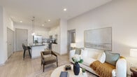 Located at 6163 Kempsville Cir in Norfolk, VA, this well-appointed 2-bedroom, 2-bathroom residence offers a thoughtfully designed single-level open-concept floor plan. The kitchen serves as a centerpiece of the home, showcasing white shaker cabinetry, dark granite countertops, a white subway tile backsplash, and a full suite of stainless steel appliances including a French door refrigerator, range, microwave, and dishwasher. A large kitchen island with dark countertop and seating for multiple guests is illuminated by elegant pendant lighting, making it ideal for both cooking and casual dining. The living room is bright and inviting, featuring large windows and a glass door that allow abundant natural light and views of the surrounding greenery. Light wood-style flooring flows throughout the main living areas, complementing the neutral color palette. The spacious primary bedroom includes plush carpeting, large windows, and a dedicated closet. The primary bathroom features white cabinetry, dark granite countertops, a wide vanity mirror, and direct access to a walk-in closet. The second bedroom is equally well-lit with generous window placement. Two closets provide ample storage throughout the home.