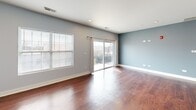 Located at 213 N Walnut St in Bensenville, Illinois, this single-floor, two-bedroom, two-bathroom residence offers a well-organized layout with a generous overall footprint. The open-concept kitchen and living area serves as the heart of the home, showcasing rich hardwood flooring that extends throughout the space. The kitchen is outfitted with white shaker-style cabinetry, dark granite countertops, stainless steel appliances including a gas range, microwave, and refrigerator, and a peninsula with pendant lighting that provides both additional prep space and a casual dining option. The living room is bright and open, featuring a ceiling fan, large windows that invite natural light, and light gray walls that complement the warm tones of the flooring. The spacious primary bedroom includes a sizable walk-in closet with wire shelving, offering ample storage. The second bedroom features hardwood floors, a window with blinds, and a clean, neutral palette. Both bathrooms are finished with tile flooring, white vanities with chrome hardware, and cool-toned accent walls, creating a modern, cohesive aesthetic throughout the residence.