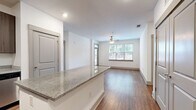Located at 1021 Glenn Valley Lane in Indian Trail, NC, this single-floor, 2-bedroom, 2-bathroom home offers a well-designed layout with consistent wood-style flooring and a clean, modern aesthetic throughout. The open-concept kitchen and living area serves as the heart of the home, featuring rich, dark cabinetry, granite countertops, a full suite of stainless steel appliances—including a refrigerator, range, microwave, and dishwasher—and a central island that provides additional prep and dining space. Recessed lighting illuminates the kitchen, which flows seamlessly into the living room. The living room is bright and welcoming, with large windows that invite natural light and a ceiling fan overhead. A glass-panel door provides direct access to the outdoors. Both bedrooms are comfortably sized, with the primary bedroom offering a dedicated walk-in closet with wire shelving. Each bedroom features ceiling fans and windows with outdoor views. The two bathrooms are well-appointed; one includes a tiled tub-shower surround with granite vanity and dark cabinetry, while the other offers a clean, white tub-shower combo. White walls, clean baseboards, and consistent finishes create a cohesive and move-in-ready environment throughout the home.
