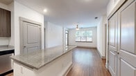 Located at 1021 Glenn Valley Lane in Indian Trail, NC, this single-floor, 2-bedroom, 2-bathroom home offers a well-designed layout with consistent wood-style flooring and a clean, modern aesthetic throughout. The open-concept kitchen and living area serves as the heart of the home, featuring rich, dark cabinetry, granite countertops, a full suite of stainless steel appliances—including a refrigerator, range, microwave, and dishwasher—and a central island that provides additional prep and dining space. Recessed lighting illuminates the kitchen, which flows seamlessly into the living room. The living room is bright and welcoming, with large windows that invite natural light and a ceiling fan overhead. A glass-panel door provides direct access to the outdoors. Both bedrooms are comfortably sized, with the primary bedroom offering a dedicated walk-in closet with wire shelving. Each bedroom features ceiling fans and windows with outdoor views. The two bathrooms are well-appointed; one includes a tiled tub-shower surround with granite vanity and dark cabinetry, while the other offers a clean, white tub-shower combo. White walls, clean baseboards, and consistent finishes create a cohesive and move-in-ready environment throughout the home.