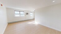 Located at 921 Tyson Ave in Philadelphia's 19111 zip code, this single-floor, one-bedroom, one-bathroom unit offers a thoughtfully laid-out living space with a clean, modern aesthetic. Light-toned hardwood flooring runs throughout, lending a bright and cohesive feel to every room.

The spacious living room is bathed in natural light from multiple windows and features baseboard heating along the exterior wall, complemented by a wall-mounted air conditioning unit for year-round comfort. Recessed lighting adds to the well-lit atmosphere.

The bedroom is a comfortable, well-proportioned room with its own window for natural light, a baseboard heater, and a built-in double closet with bi-fold doors — providing ample storage. A second closet is also available within the unit, offering additional organizational space.

The bathroom is finished with large-format, light gray tile surrounding a full soaking tub, accented by sleek matte black fixtures that add a contemporary touch. The kitchen and hallway complete the floor plan, connecting the spaces efficiently.

Throughout the unit, crisp white walls and clean trim work reinforce a modern, move-in-ready presentation. The overall ambiance is bright, minimalist, and functional — well-suited for those seeking a tidy, low-maintenance living space in Philadelphia.