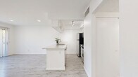 Located at 7833 Ventura Canyon Ave in Los Angeles, CA, this single-story one-bedroom, one-bathroom unit offers a well-organized and efficiently designed layout. The open-concept living and kitchen area forms the heart of the space, featuring light grey wood-style flooring that runs throughout, crisp white walls, and recessed lighting that keeps the interior bright and airy. The kitchen is equipped with stainless steel appliances, white cabinetry, a peninsula with an integrated sink, and track lighting overhead, blending functionality with a clean modern aesthetic. The living area is anchored by a built-in wall of shelving and opens directly to the outdoors through a full-height sliding glass door dressed with vertical blinds, allowing abundant natural light and a seamless indoor-outdoor connection. The bedroom is a comfortable, well-proportioned room with plush carpet flooring, mirrored sliding closet doors, and its own sliding glass door access, further enhancing the sense of light and openness. The bathroom maintains the home's clean, neutral palette with light wood-style tile flooring, white cabinetry, a stone-finish countertop, a mirrored medicine cabinet, and a full tub-shower combination with a window above for natural ventilation. Overall, the space presents a cohesive, modern, and move-in-ready aesthetic throughout.