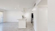 Located at 7833 Ventura Canyon Ave in Los Angeles, CA, this single-story one-bedroom, one-bathroom unit offers a well-organized and efficiently designed layout. The open-concept living and kitchen area forms the heart of the space, featuring light grey wood-style flooring that runs throughout, crisp white walls, and recessed lighting that keeps the interior bright and airy. The kitchen is equipped with stainless steel appliances, white cabinetry, a peninsula with an integrated sink, and track lighting overhead, blending functionality with a clean modern aesthetic. The living area is anchored by a built-in wall of shelving and opens directly to the outdoors through a full-height sliding glass door dressed with vertical blinds, allowing abundant natural light and a seamless indoor-outdoor connection. The bedroom is a comfortable, well-proportioned room with plush carpet flooring, mirrored sliding closet doors, and its own sliding glass door access, further enhancing the sense of light and openness. The bathroom maintains the home's clean, neutral palette with light wood-style tile flooring, white cabinetry, a stone-finish countertop, a mirrored medicine cabinet, and a full tub-shower combination with a window above for natural ventilation. Overall, the space presents a cohesive, modern, and move-in-ready aesthetic throughout.
