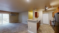 Located in Airway Heights, WA, this two-bedroom, two-bathroom residence offers a practical and comfortable single-floor layout. The open-concept living and kitchen area forms the heart of the home, where a peninsula with a countertop overhang and warm wood cabinetry separates the kitchen from the carpeted living space. The kitchen is fully equipped with a range, dishwasher, built-in microwave, and generous counter space, complemented by tile flooring for easy maintenance. The living area features a wall-mounted HVAC unit and sliding glass doors that open onto a private balcony with views of the surrounding neighborhood. Both bedrooms are carpeted and feature wall HVAC units; the primary bedroom is comfortably sized, while the second bedroom benefits from natural light through a window. Each bathroom is finished with warm wood vanity cabinetry, tile flooring, and a vanity mirror with overhead lighting. The primary bath includes a full soaking tub and shower combination, while the second bath offers a more compact layout with a tall storage cabinet. Neutral, warm-toned walls and consistent finishes throughout give the home a cohesive and move-in-ready feel.