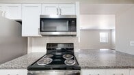 This 2-bedroom, 2-bathroom single-floor residence offers a thoughtfully designed layout with a clean, modern aesthetic throughout. Light wood-style flooring flows consistently across the living room, bedrooms, hallway, and kitchen, creating a cohesive and inviting atmosphere.

The kitchen is well-equipped with granite countertops, white shaker-style cabinetry, a classic white subway tile backsplash, and stainless steel appliances including an electric range with over-the-range microwave and a full-size refrigerator. The open sightline from the kitchen into the living room enhances the sense of space.

The living room is bright and open, benefiting from natural light filtering through window blinds. Both bedrooms are generously proportioned, with the primary bedroom offering a comfortable footprint, light-toned walls, and a ceiling fan with integrated lighting. Each bedroom features windows with blinds and easy access to the hallway.

Both bathrooms maintain the home's neutral palette, featuring wood-look tile flooring, white vanities, tiled tub-surround showers, and brushed nickel hardware and towel bars. A dedicated closet provides additional storage. The overall design is clean, functional, and move-in ready.