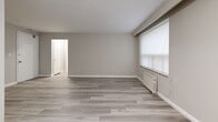 Located at 75 Windermere Ave, Suite 310 in Toronto's Swansea neighbourhood, this one-bedroom, one-bathroom unit offers a thoughtfully laid-out single-floor plan finished with contemporary light grey laminate flooring throughout. The open living and dining area is a standout feature, boasting dual windows fitted with roller blinds that fill the space with natural light, complemented by classic white radiator units beneath each window. The neutral grey and white colour palette lends a clean, modern ambiance throughout. The galley-style kitchen is efficiently designed with crisp white shaker cabinetry, dark countertops, a stainless steel sink, and full-size stainless steel appliances including a refrigerator and stove. The bedroom is a comfortable, well-proportioned space featuring its own window with a radiator below and a mirrored sliding-door closet that enhances the sense of space. A second closet provides additional storage. The bathroom is finished in bright white subway tile surrounding a full soaker tub with shower, paired with a pedestal-style sink and mirrored medicine cabinet. A dedicated entrance and additional unclassified space complete this practical, move-in-ready unit.