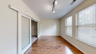 Located at 1901 S Charles St in Baltimore's South Baltimore neighborhood, this one-bedroom, one-bathroom unit offers a thoughtfully designed layout across a single floor. The living area is highlighted by warm hardwood flooring, neutral cream-toned walls, and stylish track lighting overhead. Natural light flows in through multiple windows fitted with horizontal blinds, creating a bright and inviting atmosphere. A frosted glass sliding door connects the living space to the bedroom, adding a modern architectural touch while maintaining an open feel.

The bedroom continues the hardwood flooring and benefits from a pair of large windows that invite ample natural light. A dedicated closet with carpeted flooring provides practical storage.

The galley-style kitchen is well-appointed with rich, dark espresso cabinetry featuring a decorative wine rack, granite countertops, a stainless steel sink, and a full suite of black appliances. Light tile flooring runs through the kitchen and into the hallway, which leads to the entrance.

The bathroom is finished with the same dark cabinetry and granite vanity countertop, complemented by light tile floors, a full tub-shower combo with white tile surround, and brushed nickel fixtures throughout. This unit offers a clean, modern aesthetic suited for comfortable everyday living.