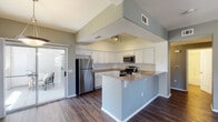 This single-floor residence offers a thoughtfully designed open-concept layout that seamlessly connects the living, dining, and kitchen areas. Rich, dark hardwood-style flooring runs throughout the main living spaces, complementing the neutral gray-toned walls and creating a cohesive, modern aesthetic.

The kitchen is a functional centerpiece, featuring white cabinetry, granite countertops, stainless steel appliances including a refrigerator, gas range, and microwave, and a peninsula with bar seating. Track lighting illuminates the workspace, while a sliding glass door provides direct access to an outdoor patio area, filling the space with natural light.

The living room is generously proportioned, with a built-in fireplace, a ceiling fan, and large windows dressed with vertical blinds that invite ample natural light. The open sightlines between the kitchen and living area enhance the sense of spaciousness.

The bedrooms are carpeted for comfort and each feature ceiling fans and walk-in closets with wire shelving. Two full bathrooms serve the residence, each finished with white cabinetry, a tub-shower combination, and hardwood-style flooring. A dedicated in-unit laundry room with a full-size washer and dryer adds everyday convenience. Overall, the space presents a clean, practical, and comfortable living environment.