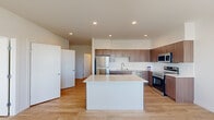 This well-designed single-floor residence offers 2 bedrooms and 3 bathrooms within a thoughtfully laid-out floor plan connected by two hallways. The open-concept kitchen and living area serves as the heart of the home, showcasing a large center island with a light quartz countertop, warm wood-grain cabinetry, white subway tile backsplash, and a full suite of stainless steel appliances including a refrigerator, range, microwave, and dishwasher. Recessed lighting illuminates the space throughout.

Light hardwood flooring flows consistently across the entire unit, contributing to a clean, cohesive aesthetic. The primary bedroom features a window with outdoor views and a ceiling fan, while the second bedroom also benefits from natural light and an outdoor view. Both rooms maintain the unit's minimalist, modern character with crisp white walls.

The three bathrooms include fixtures with wood-toned cabinetry and light countertops, with one bathroom incorporating a stacked washer and dryer unit alongside a full soaking tub. The hallways connect the rooms efficiently, and the overall design prioritizes clean lines, neutral tones, and natural light throughout.