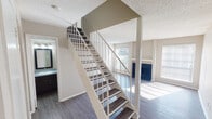 Located at 2836 Sharpview Ct in Fort Worth, Texas, this two-story home offers a practical and well-appointed layout across both levels. The interior is unified by durable wood-look plank flooring that runs throughout the main living areas and bedrooms, lending a cohesive and modern feel to the space.

A striking open staircase with a cream-painted metal railing connects the two floors, serving as a functional centerpiece visible from the main living area. The living room features a blue accent fireplace surround and windows that allow natural light to filter in, creating a bright and welcoming atmosphere. Textured ceilings are present throughout the home.

The kitchen is equipped with dark espresso cabinetry, speckled countertops, a double stainless steel sink with a modern faucet, and a bold mosaic tile backsplash in blue and white tones, adding a distinctive design element to the space.

The bedrooms are generously proportioned, each outfitted with ceiling fans with integrated lighting and closet space. Natural light enters through slatted window blinds, contributing to a comfortable ambiance in every room.

The bathrooms feature full tub-shower combinations with white tile surrounds, dark-framed vanity mirrors, dark cabinetry with speckled countertops, and updated brushed nickel fixtures, providing a clean and functional finish throughout.