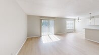 Located in Tukwila, WA, this 2-bedroom, 2-bathroom single-floor residence offers a clean, functional layout with a bright and neutral aesthetic throughout. The open living room is a standout feature, showcasing light wood-style flooring, soft natural light streaming in through a sliding glass door fitted with vertical blinds, and an additional window that further enhances the airy feel of the space. A baseboard heating unit ensures year-round comfort.

The galley-style kitchen is efficiently designed with ample white cabinetry extending to the ceiling for generous storage, light-toned countertops, a white appliance suite including a refrigerator and electric range, and a single-basin sink. The light wood flooring continues seamlessly from the living area into the kitchen.

Both bedrooms feature plush wall-to-wall carpeting and neutral gray-toned walls. The primary bedroom offers a comfortable footprint with a window bringing in outdoor views. Both bathrooms are appointed with warm earth-toned tile surrounding full tub and shower combinations, light wood flooring, and white vanity cabinetry. A hallway connects the rooms, providing a logical and practical flow throughout the home.