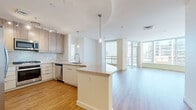 Located in the heart of downtown Phoenix, this modern residence on W Monroe Street offers a well-designed single-floor layout encompassing two living areas, two bathrooms, a full kitchen, and a walk-in closet. Warm hardwood-style flooring flows throughout the entire unit, lending a sense of continuity and warmth across all spaces.

The open-concept kitchen and living area serves as the centerpiece of the unit. The kitchen is equipped with stainless steel appliances, including a gas range, microwave, refrigerator, and dishwasher. Light wood cabinetry pairs with a marble-style backsplash and a quartz-topped island, which doubles as a breakfast bar and is accented by sleek pendant lighting. The layout transitions seamlessly into a spacious living area bathed in natural light from floor-to-ceiling glass windows and a sliding door that opens to a balcony with sweeping downtown Phoenix views.

A second living area provides additional flexible space, also benefiting from large windows overlooking the cityscape. The primary bathroom features a dual-sink vanity with white cabinetry, a soaking tub clad in richly textured stone tile, and mixed-material flooring that adds a sophisticated contrast. The walk-in closet offers generous storage with built-in hanging rods. The overall ambiance is clean, contemporary, and light-filled throughout.