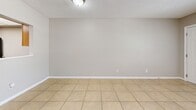 Located at 600 Wildwood Way in Clearwater, Florida, this single-story, one-bedroom, one-bathroom unit offers a practical and well-organized layout. Light beige ceramic tile flooring runs consistently throughout the entire space, contributing to a clean and cohesive look. Neutral gray walls and textured ceilings complement the bright, understated aesthetic found in each room.

The galley-style kitchen is a functional standout, featuring warm honey-toned wood cabinetry, dark granite countertops, a stainless steel sink, and black appliances including a range and refrigerator. A panel skylight overhead provides ample illumination to the workspace. The kitchen opens into a combined dining area, which benefits from a window that lets in natural light.

The bedroom is a well-proportioned space with a closet, a window overlooking greenery outside, and a textured ceiling. Its tile flooring and neutral walls provide a calm, versatile backdrop. The bathroom is straightforward and functional, featuring a full-size soaking tub with a tiled surround and a shower fixture.

Throughout the unit, clean white baseboards frame each room neatly, and the single-floor layout ensures easy accessibility. This Clearwater residence offers a no-frills, functional living environment with consistent finishes throughout.