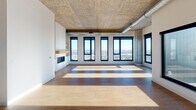 Located at 333 E Hennepin Ave in Minneapolis, this high-rise unit blends industrial character with contemporary finishes throughout its well-appointed single-floor layout. Exposed concrete ceilings with visible ductwork establish an urban aesthetic that carries through the open living areas, which are anchored by warm hardwood flooring and flooded with natural light from expansive black-framed windows offering sweeping views of the Minneapolis skyline and surrounding cityscape.

The chef's kitchen is a standout, featuring sleek white cabinetry, a large center island with a white quartz countertop, stainless steel appliances including a double wall oven and refrigerator, and stylish black pendant lighting suspended from the textured concrete ceiling. The open layout connects seamlessly to the main living area, which features a private balcony access point and generous wall space framed by raw concrete columns.

The bedrooms are bright and airy, with floor-to-ceiling windows that maximize the elevated views, complemented by a spacious walk-in closet with built-in shelving and hanging rods. The primary bathroom offers a clean, modern design with herringbone tile flooring, a backlit vanity mirror, dark wood cabinetry, and a combined soaking tub and glass-enclosed shower. A separate half bath features similar refined finishes. In-unit laundry with a full-size washer and dryer adds everyday convenience.