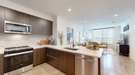 This well-designed 2-bedroom, 2-bathroom residence in Walnut Creek, CA offers a thoughtful single-level floor plan with modern finishes throughout. The open-concept living, dining, and kitchen area serves as the heart of the home, featuring light wood-style flooring, recessed lighting, and large windows that fill the space with natural light. The kitchen is outfitted with rich dark wood cabinetry, a tile backsplash, quartz countertops, stainless steel appliances including a range, microwave, and refrigerator, and a peninsula with bar seating that flows seamlessly into the dining area. The living room offers a comfortable, bright atmosphere with generous window coverage. Both bedrooms are well-proportioned, with the primary bedroom featuring a ceiling fan, large windows, and access to a spacious walk-in closet with adjustable shelving systems. Each bedroom is served by its own full bathroom, both finished with floating dark wood vanities, large-format tile flooring, and bright vanity lighting. One bathroom includes a soaking tub with shower, while the other features a glass-enclosed walk-in shower with marble-style tile surround. A hallway connects the rooms efficiently, completing a functional and refined layout ideal for comfortable living.