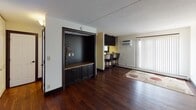 Located at 3535 Bryant Ave S in Minneapolis, Minnesota, this single-floor residence offers a well-designed layout with a cohesive blend of modern finishes and functional living spaces. Rich, dark hardwood flooring runs throughout the unit, providing a warm and consistent aesthetic from room to room.

The open-concept kitchen is a standout feature, outfitted with dark cabinetry, granite-style countertops, and black appliances including a gas range and microwave. A breakfast bar with pendant lighting overhead and two upholstered bar stools creates a casual dining area that connects seamlessly to the living space.

The living room is generously proportioned, bathed in natural light through large vertical-blind-covered sliding doors. A built-in media cabinet with dark cabinetry and a granite-top surface adds both style and storage to the living area.

The bathroom is neatly appointed with a rich wood vanity, ample drawer storage, a well-lit mirror above the sink, and a shower-tub combo. Neutral wall tones carry throughout the unit, complementing the darker accents of the cabinetry and flooring. The overall ambiance is clean, contemporary, and move-in ready, making this Minneapolis residence a practical and attractive living space.
