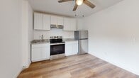 Located at 1305 Washington Avenue in Bay City, Michigan, this efficiently designed one-bedroom, one-bathroom unit makes smart use of its compact footprint. Light-toned, wood-look flooring runs throughout the entire space, lending a cohesive and clean aesthetic from entry to bedroom.

The entry hallway opens directly into the kitchen and living area, where white shaker-style cabinetry paired with granite countertops and stainless steel appliances — including a range with hood, refrigerator, and sink — create a modern, functional cooking space. A ceiling fan overhead keeps the area comfortable and well-ventilated. A wall-mounted PTAC unit provides climate control in both the entry and main living areas.

The bedroom is a well-proportioned, bright room featuring the same warm wood-look flooring and a ceiling fan, offering a comfortable and private retreat. Six-panel white doors are consistent throughout, contributing to the space's clean, uniform design.

The bathroom includes a white vanity with an integrated sink, a mirror, and chrome fixtures, maintaining the space's crisp, neutral palette. A dedicated laundry area with a stacked washer and dryer unit adds practical convenience within the unit itself.

Overall, this space presents a tidy, updated interior with consistent finishes throughout, well-suited for efficient single-occupancy living in Bay City.