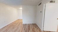 This 1-bedroom, 1-bathroom unit offers a thoughtfully organized layout across a single floor, making efficient use of every square foot. The combined kitchen and living area forms the heart of the space, with the kitchen standing out as a functional highlight. It features white shaker-style cabinetry, dark granite-style countertops, and a full suite of stainless steel appliances including a refrigerator, electric range, and dishwasher. Light hardwood-style flooring runs consistently throughout the unit, lending a clean, cohesive aesthetic.

The living area is bright and open, with a large window allowing natural light to fill the room and offering a view to the outdoors. A front entry door with an adjacent window further enhances the sense of light and connectivity to the exterior. The bedroom is a well-proportioned private retreat, featuring a painted brick accent wall, a window for natural light, and a closet. Textured ceilings are present throughout the unit.

The bathroom includes a full tub and shower combination with white subway tile surround, a brushed nickel grab bar, white cabinetry, and matching dark countertops consistent with the kitchen. A hallway connects the main living spaces, completing this efficient and move-in-ready floor plan.