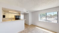 Located at 3535 West Tierra Buena Lane in Phoenix, AZ, this single-story unit offers a practical and well-organized layout across one bedroom and a combined kitchen and living area. The open-concept living and kitchen space is finished with neutral ceramic tile flooring and features a peninsula breakfast bar with a light-toned countertop and integrated sink, providing both additional prep space and a casual dining option. The kitchen is equipped with white cabinetry, a black electric range, a stainless steel microwave, and a black refrigerator, all accented by track lighting above. A textured ceiling carries throughout the main living area, adding subtle character to the clean, white walls. A large window fitted with vertical blinds allows natural light to fill the living space, offering a view of the surrounding neighborhood. The bedroom is a generously sized private retreat, carpeted for comfort, and features a wide sliding-door closet providing ample storage. An adjacent vanity area with white cabinetry and a light countertop adds convenience. The bedroom also benefits from natural light through its own window with vertical blinds. The overall aesthetic is clean, bright, and functional, making this a straightforward and comfortable space in the heart of Phoenix.
