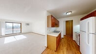 Located at 4601 Shoreline Dr in Spring Park, MN, this two-bedroom, one-bathroom residence offers a practical and well-organized single-floor layout. The galley-style kitchen features warm wood cabinetry lining both walls, light countertops, a double sink, and white appliances including a range and refrigerator, with durable hardwood-style flooring underfoot. The kitchen opens toward a combined dining and living area, where plush carpeting, a textured ceiling, and a wall-mounted air conditioning unit create a comfortable environment. A sliding glass door in the living room fills the space with natural light and provides access to a private balcony with outdoor views. Both bedrooms are carpeted and bright, each benefiting from natural light through windows with baseboard heating below. The primary bedroom offers a generous footprint with a sliding-door closet, while the second bedroom includes its own closet as well. A hallway connects the main living areas to the bedrooms and bathroom, with additional closets providing ample storage throughout. The full bathroom features classic tile flooring, a wood-toned vanity with a white countertop, and a full tub-shower combination. With four closets total, this residence maximizes storage in a compact and efficiently designed floor plan.