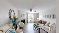 This single-floor residence offers a practical and comfortable layout across two bedrooms and two bathrooms. The living room serves as the heart of the home, featuring light wood-style flooring, a ceiling fan, and a tile-surround fireplace with a white mantel as a central focal point. Natural light filters in through large windows dressed with patterned curtains, creating a bright and welcoming atmosphere. The galley-style kitchen is efficiently designed with gray cabinetry, granite-style countertops, black appliances including a range, microwave, and refrigerator, and opens directly to a dining area with hardwood-style flooring. The primary bedroom offers plush carpeting and direct access to an en-suite bathroom, providing added privacy and convenience. The second bedroom is similarly carpeted and well-proportioned, with natural light from a window. Both bathrooms are finished with gray vanity cabinetry, granite-style countertops, and a tub-shower combination with tile surround. A dedicated in-unit laundry area with shelving adds everyday functionality. Neutral wall tones throughout the home create a cohesive and versatile backdrop, while the thoughtful layout maximizes the efficient use of the overall floor area.